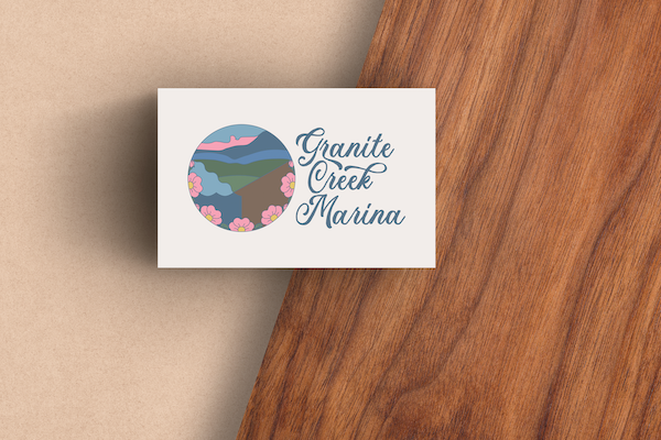 A business card featuring the Granite Creek Marina logo, sitting on a wood desk.
